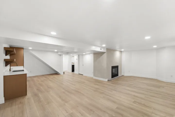 Open-concept living space featuring engineered wood-finish flooring throughout, recessed ceiling lighting, and a modern kitchen with wood cabinetry and stainless steel appliances