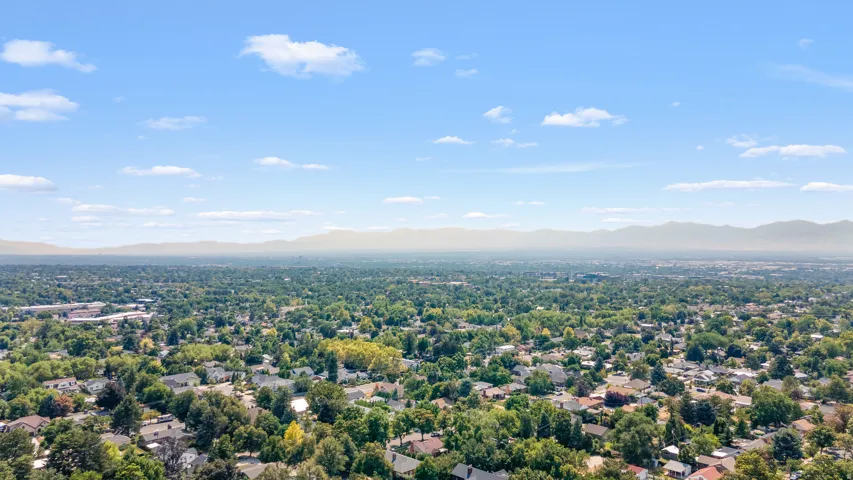 Expansive aerial perspective showcasing a residential neighborhood under a clear sky with distant mountain ranges