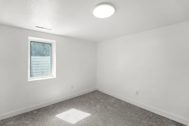 Bright, finished room featuring neutral wall finishes, recessed ceiling lighting, carpet flooring, and a large window with natural light exposure