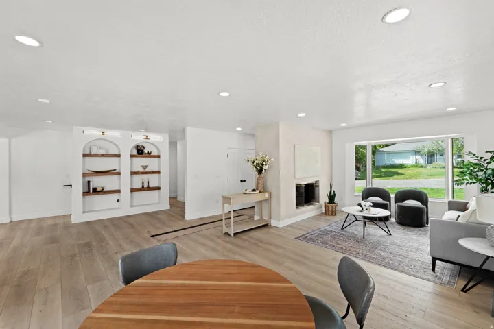 Recessed lighting, wood-finish flooring, built-in arched shelving with wood shelves, fireplace, and large picture window