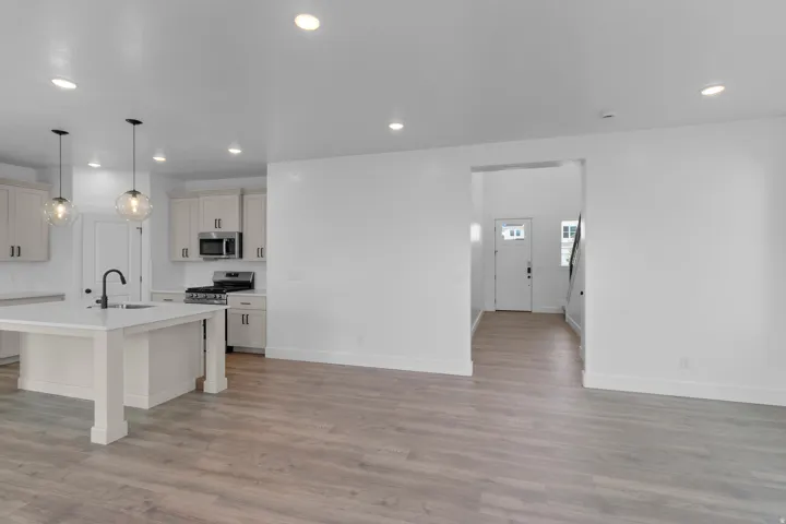 Open-concept living space featuring wood-finish flooring, recessed lighting, a kitchen island with seating, and stainless steel appliances