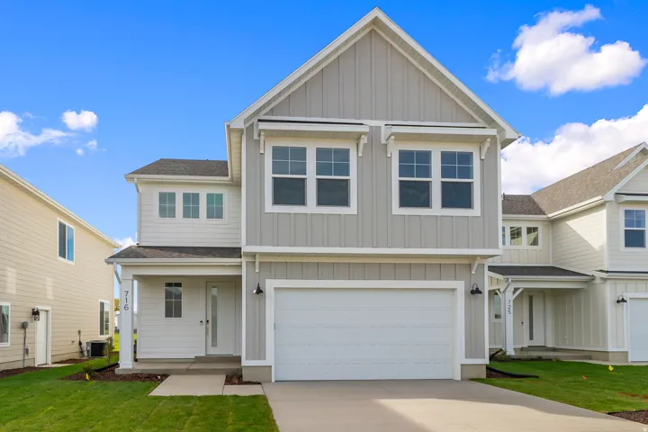 Modern two-story home featuring a striking gabled roofline with large dual windows, crisp white fiber cement siding, and a recessed entry portico