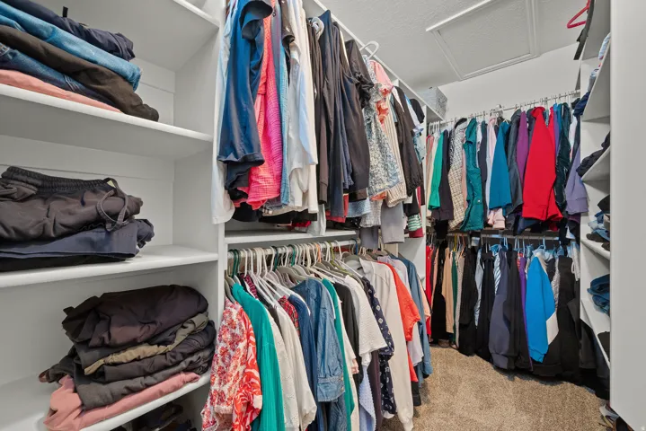 Built-in storage solutions featuring multiple hanging rods, extensive shelving, and carpet flooring