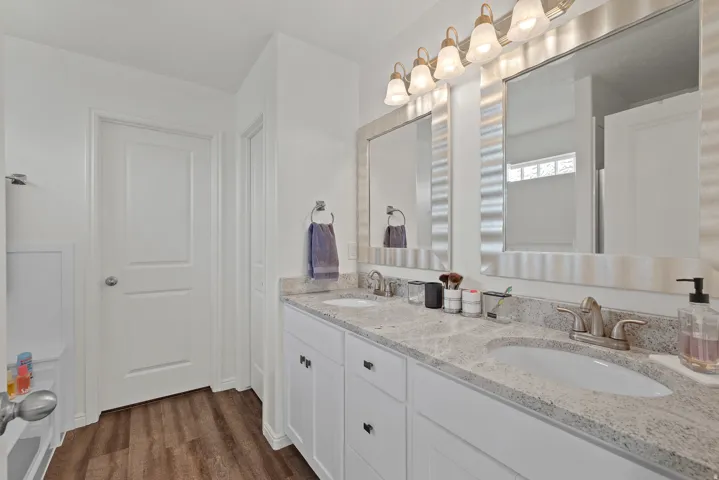 Dual vanity with undermount sinks, stone countertops, and wood-finish flooring