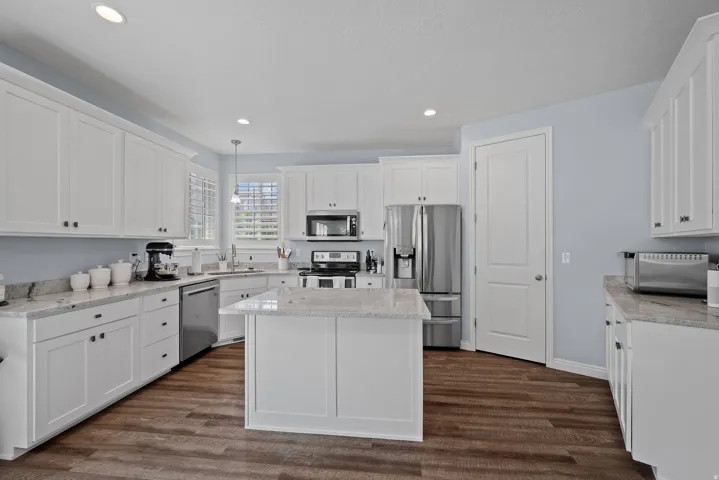 Kitchen featuring wood-finish flooring, white cabinetry, a central island, and stainless steel appliances