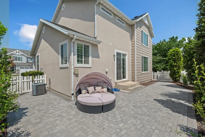Paver patio with a sliding glass door entry and a white picket fence