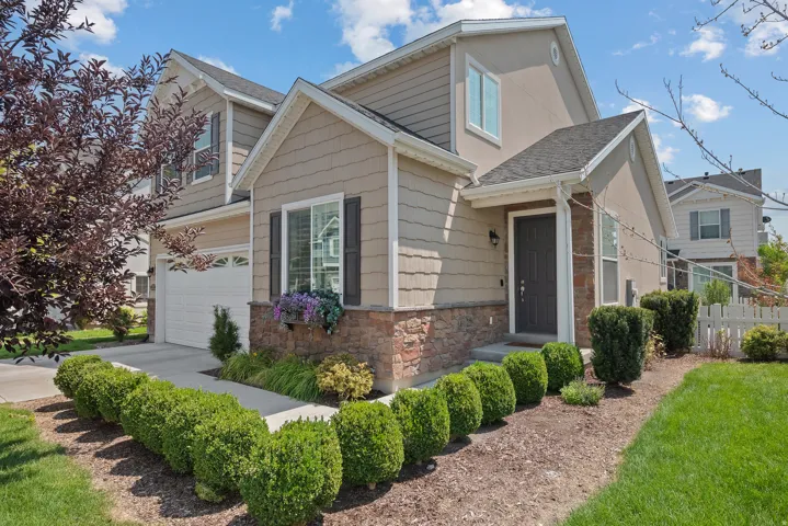 Two-story exterior with a two-car garage, stone and siding facade, and a covered entryway