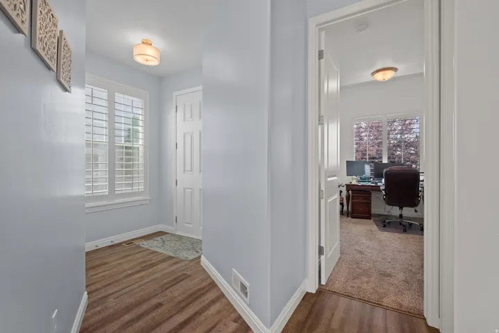 Wood-finish flooring, white plantation shutters, and a paneled entry door