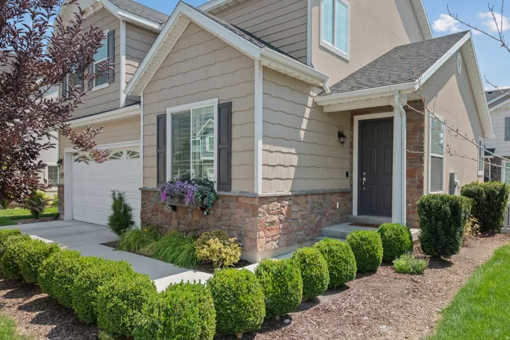 Multi-textured facade with stone and siding accents, prominent front entry, attached garage, and landscaped front yard