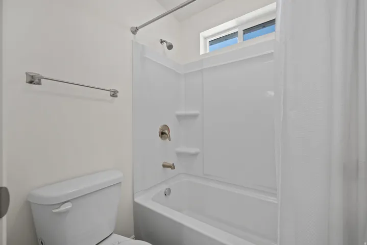 White shower/tub combination with brushed nickel fixtures and an integrated soap dish