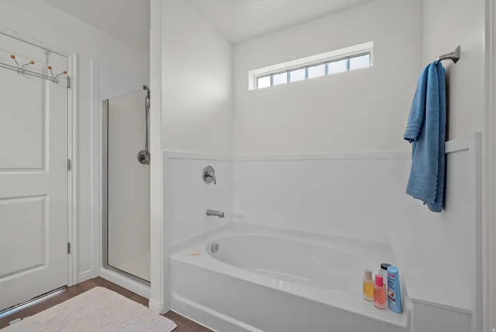 Soaking tub with chrome fixtures, a clear glass shower enclosure, and a high transom window