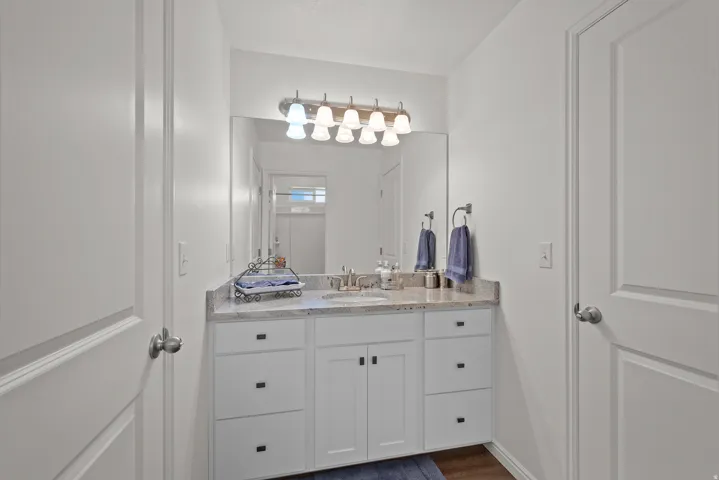 Vanity with white shaker-style cabinetry, a light-toned countertop, and an integrated sink