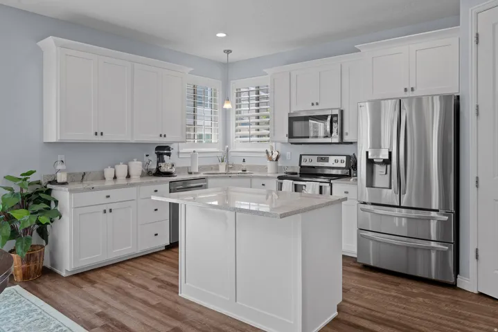 Kitchen featuring white shaker-style cabinetry, granite countertops, stainless steel appliances, a center island, and wood-finish flooring