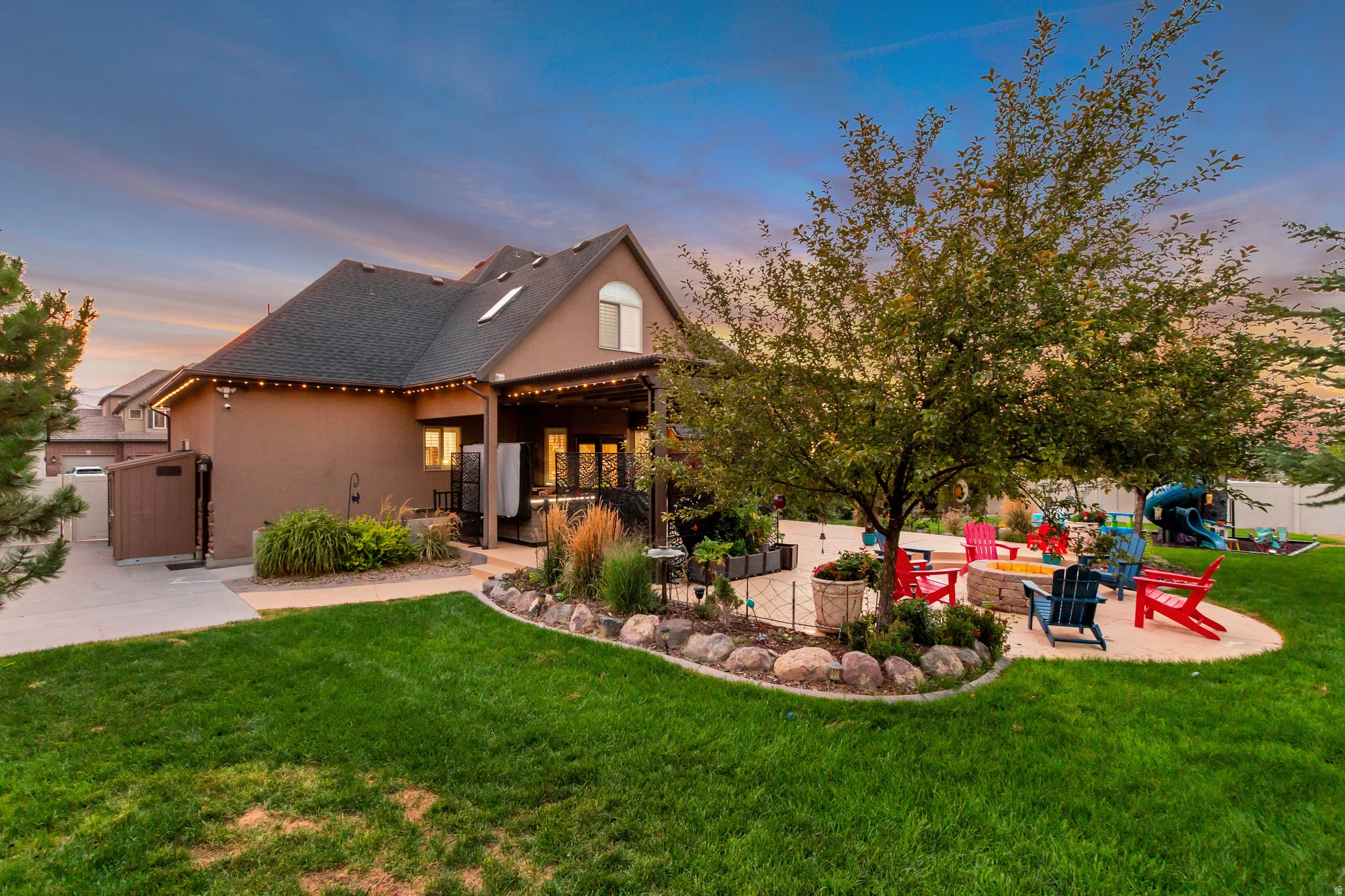 Expansive backyard featuring a manicured lawn, established landscaping, a paved patio, and a covered patio area