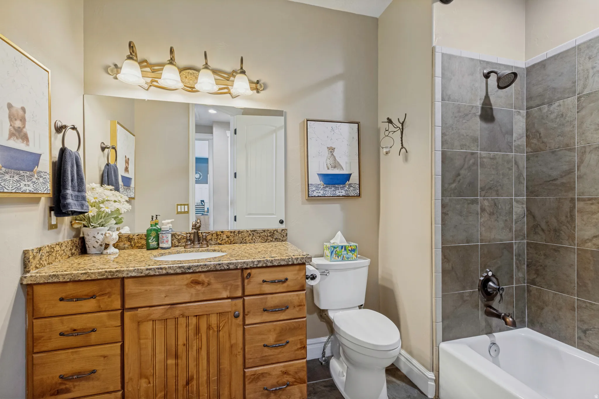 Wood-finish vanity with an integrated basin, stone countertop, and a tiled shower-tub combination