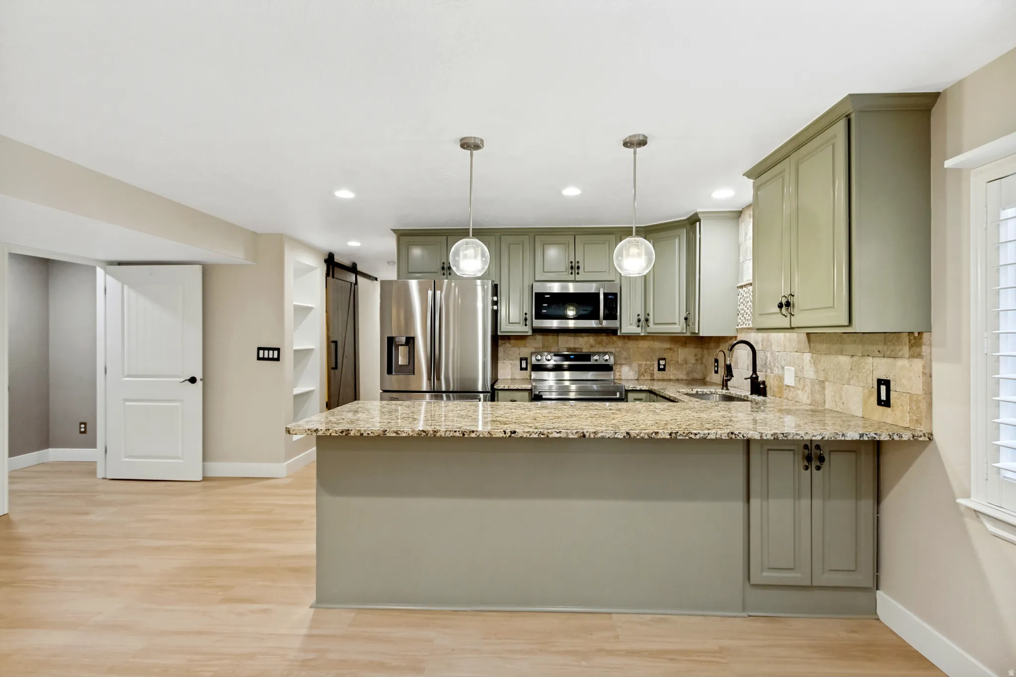 Kitchen featuring granite countertops, stainless steel appliances, wood-finish flooring, recessed lighting, and pendant light fixtures