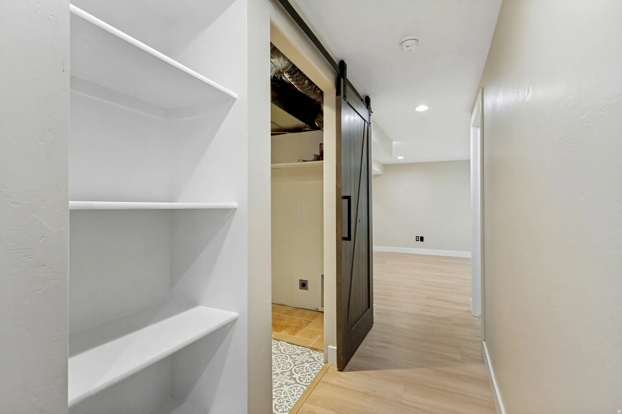 Built-in shelving, wood-finish flooring, recessed lighting, and a barn door with black hardware