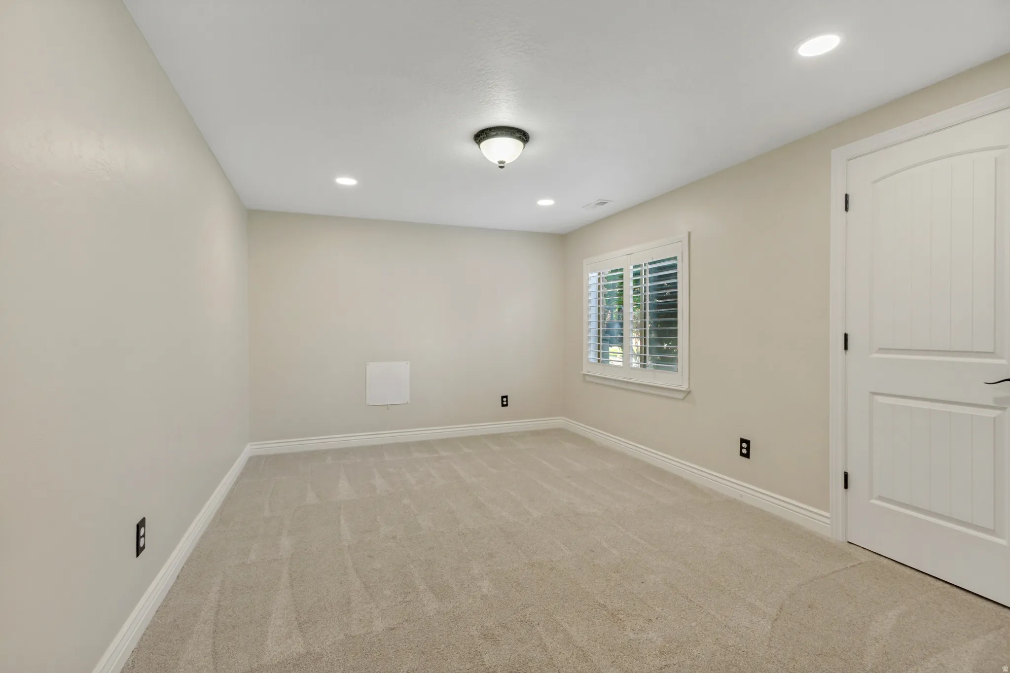 Neutral-toned carpeting, recessed lighting, ceiling-mounted light fixture, white window shutters, and a paneled interior door