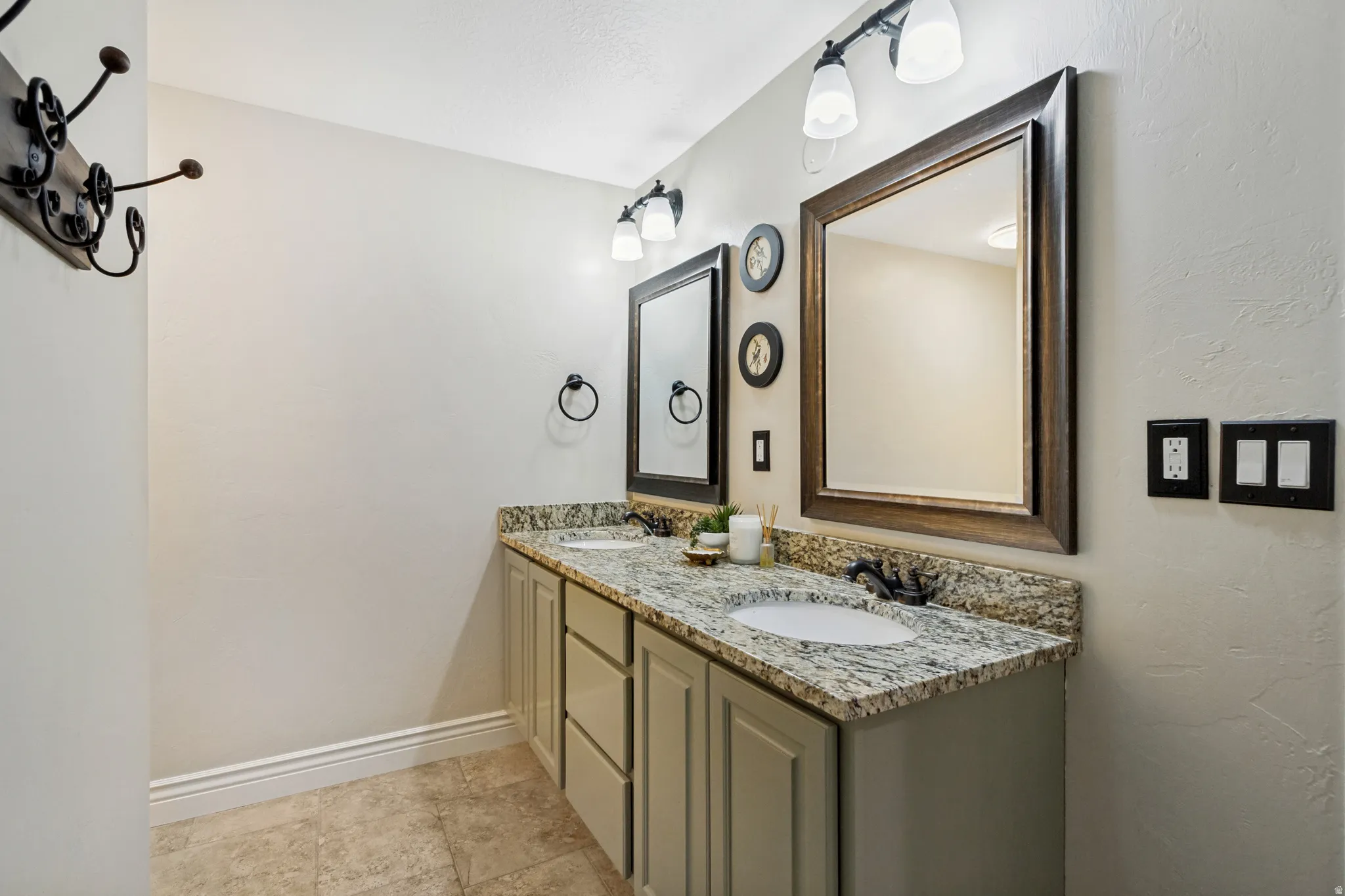 Dual vanity with granite-style countertop, undermount sinks, and dark-framed mirrors