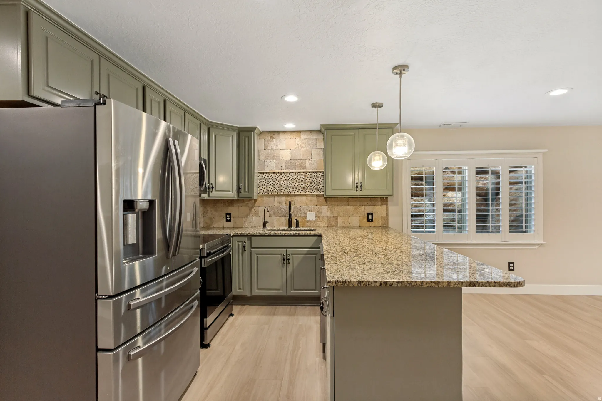 Kitchen featuring stainless steel appliances, light-toned cabinetry, granite countertops, and recessed lighting