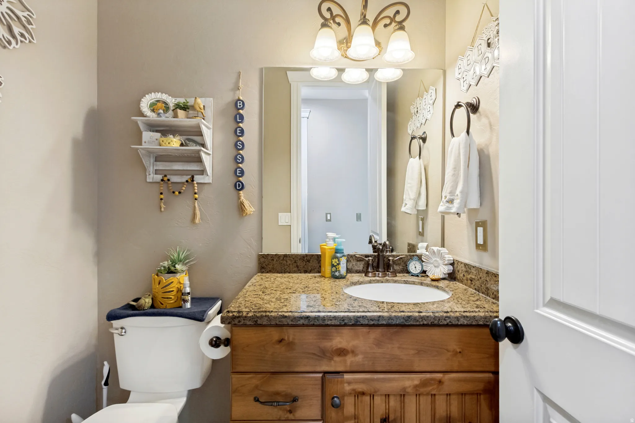 Vanity with a granite countertop, wood-finish cabinetry, and an undermount sink