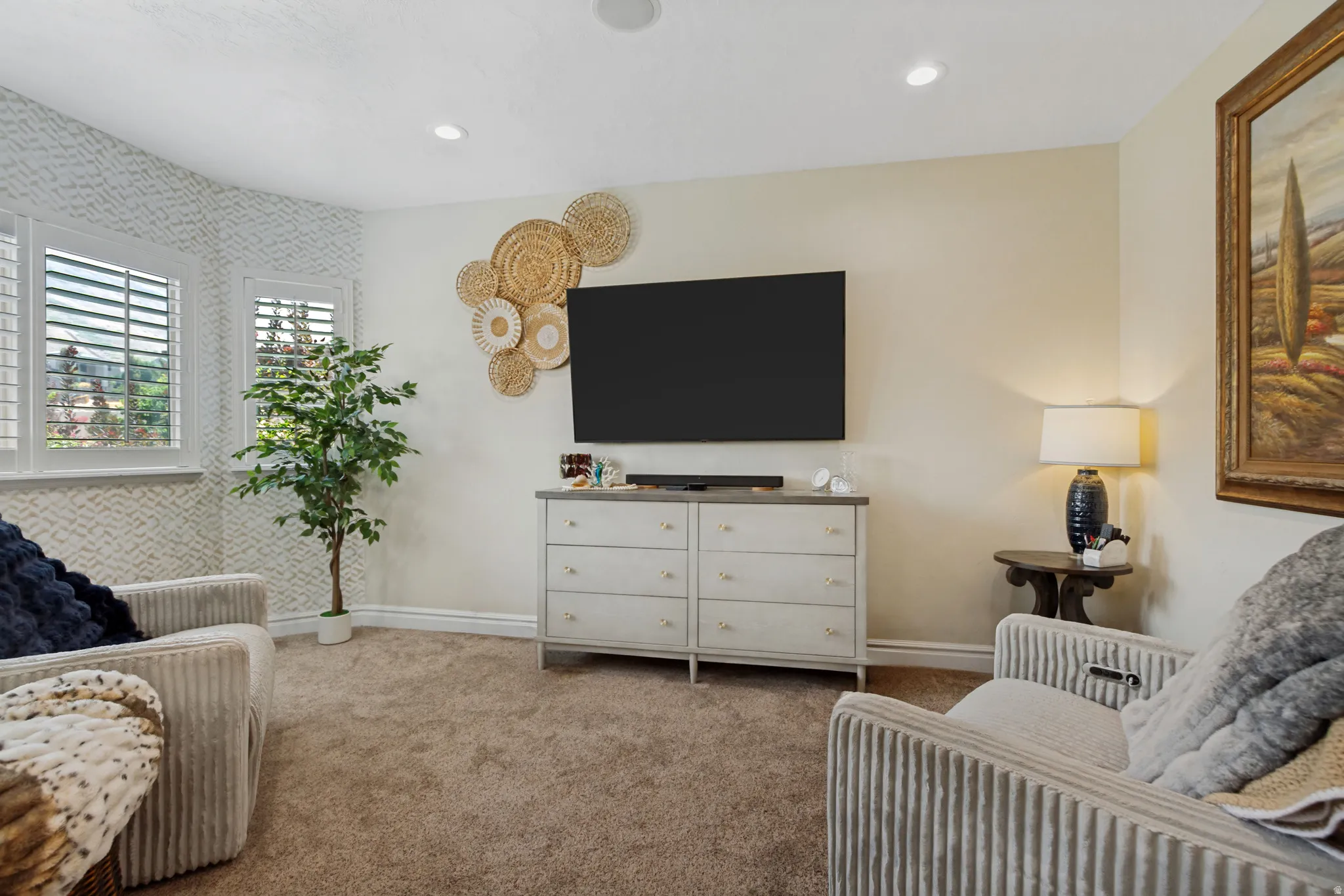 Recessed lighting, textured accent wall, plantation shutters, wall-mounted television, and carpet flooring