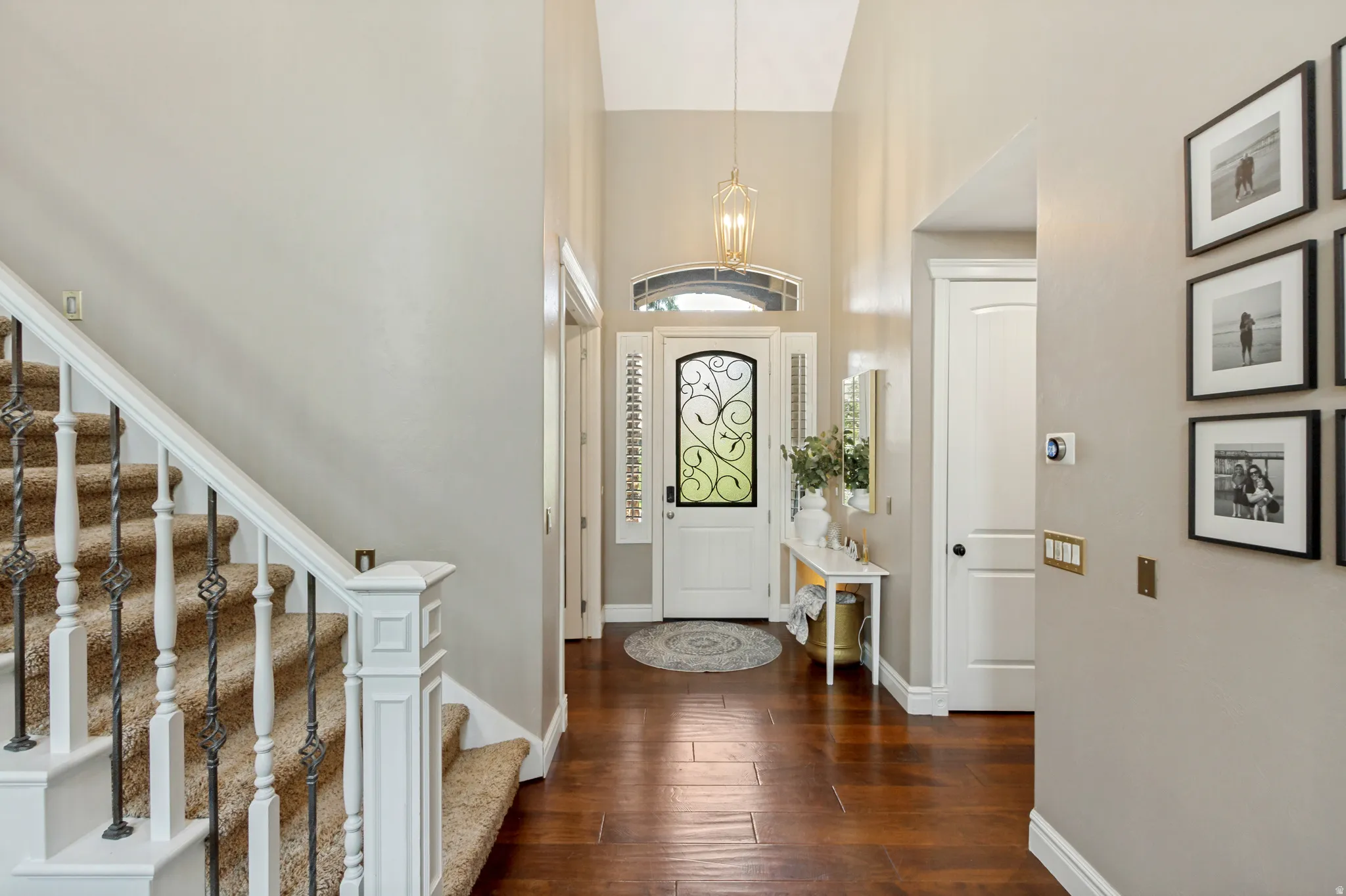 Vaulted entry with hard-surface flooring, a decorative glass entry door, and a wrought iron staircase