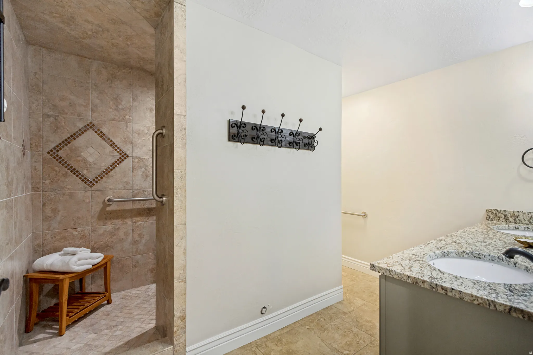 Tiled shower with grab bars and decorative accent tile