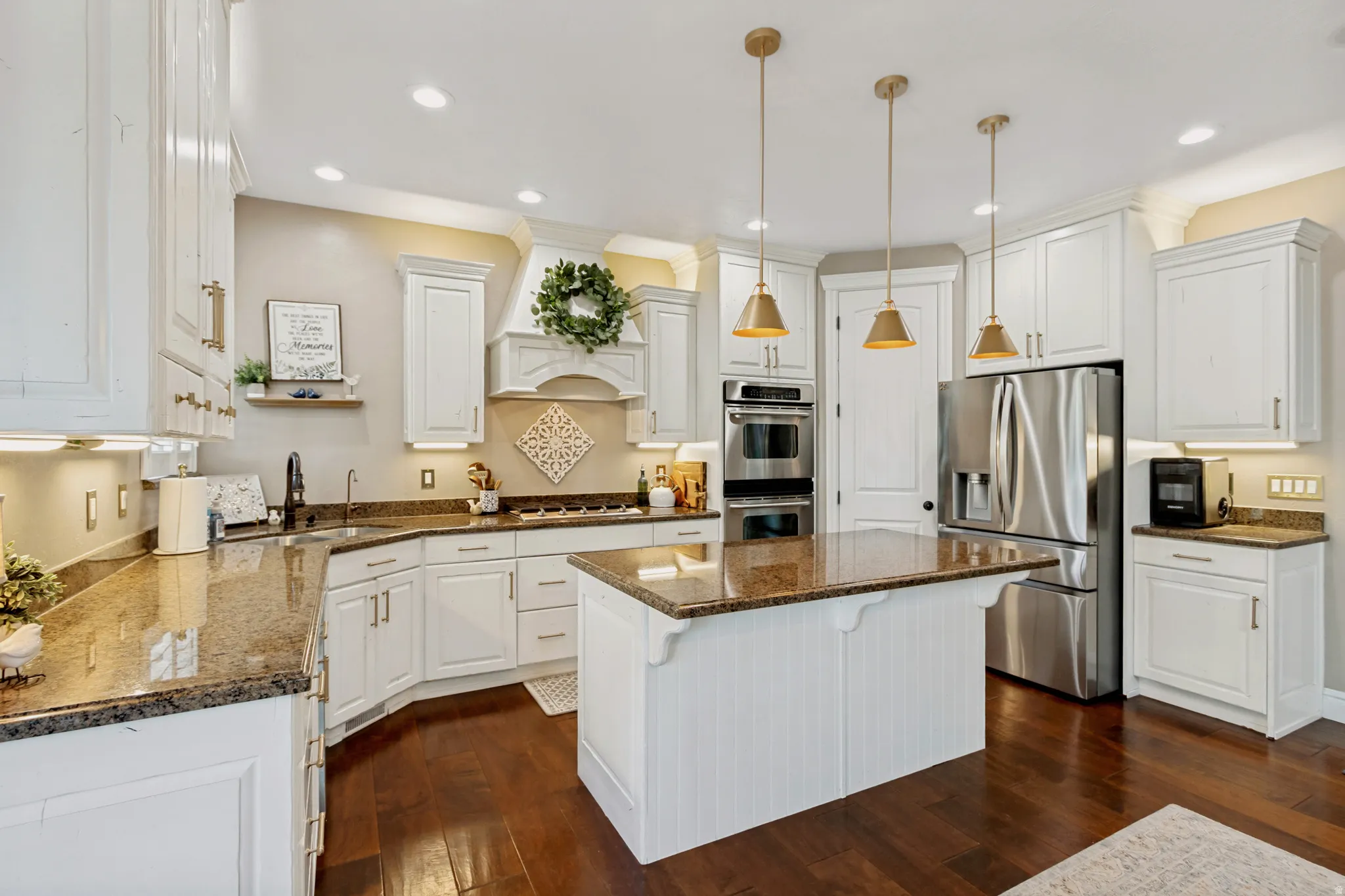 Gourmet kitchen with wood-finish flooring, white cabinetry, granite countertops, and stainless steel appliances