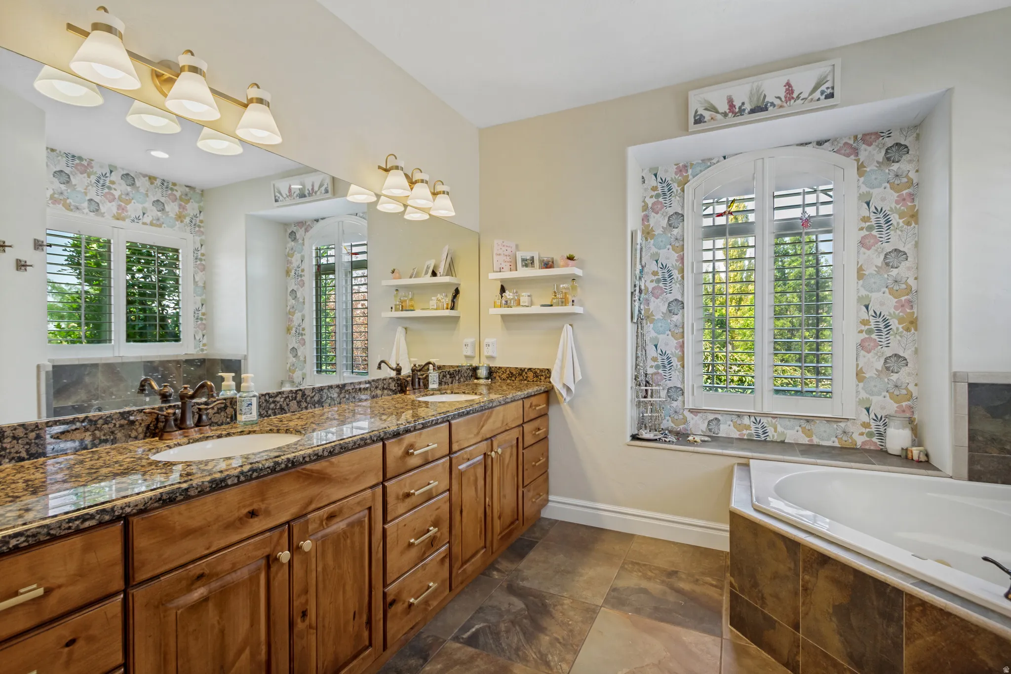 Double vanity with granite countertops, wood-finish cabinetry, and undermount sinks