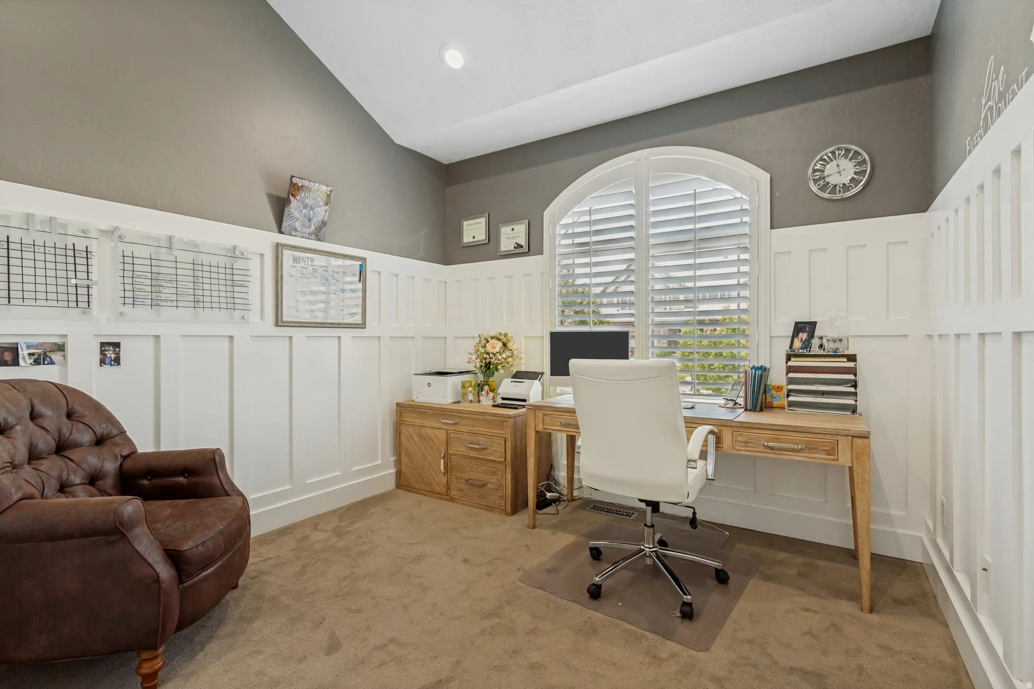 Arched window with plantation shutters, white wainscoting, vaulted ceiling, recessed lighting, and carpet flooring