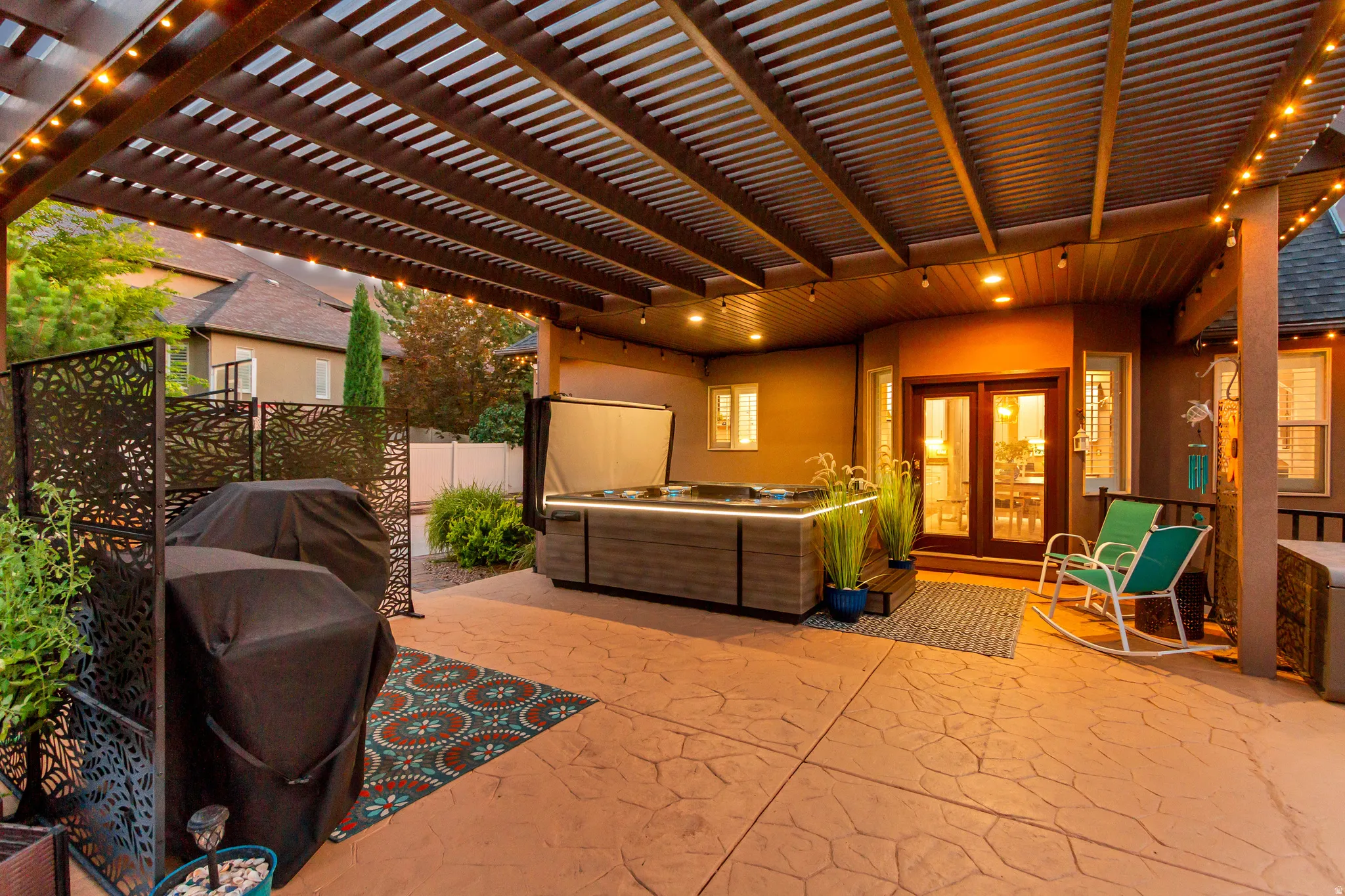 Stamped concrete patio with a slatted pergola, recessed lighting, and built-in hot tub