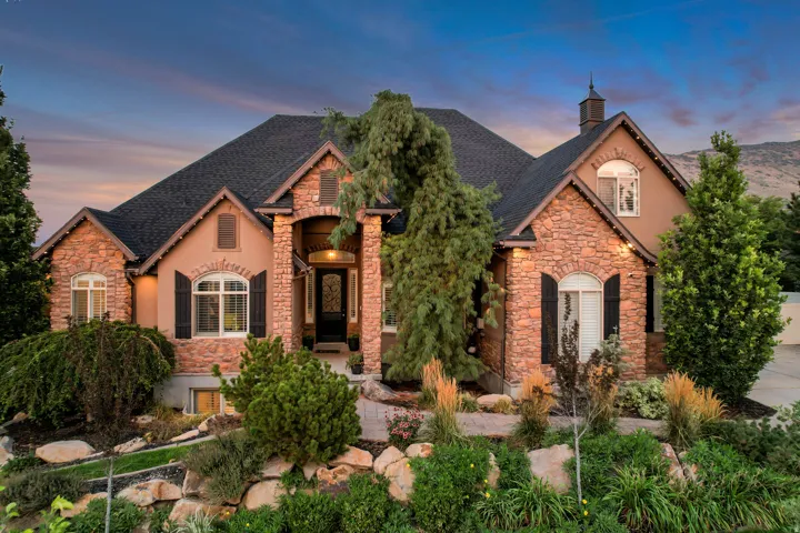 Stone and stucco exterior with multiple gables and a dark shingle roof