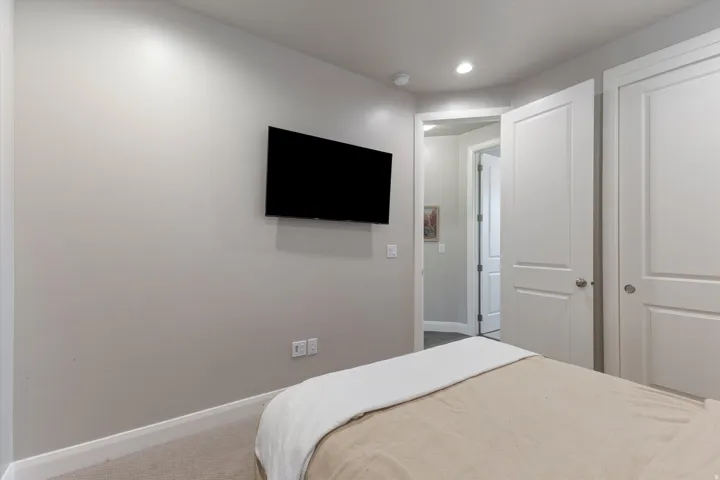 Recessed lighting, wall-mounted television, and neutral wall tones