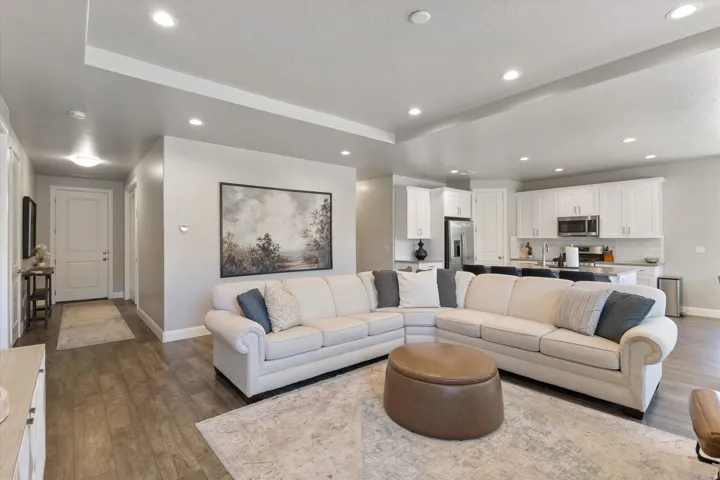 Open-concept living space featuring wood-finish flooring, recessed lighting, and a kitchen with white cabinetry and stainless steel appliances