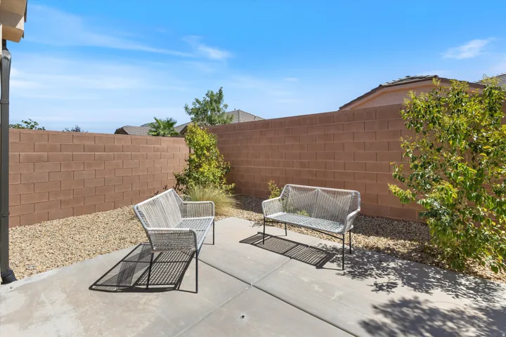 Spacious backyard retreat featuring a concrete patio, brick perimeter walls, and mature landscaping with climbing vines