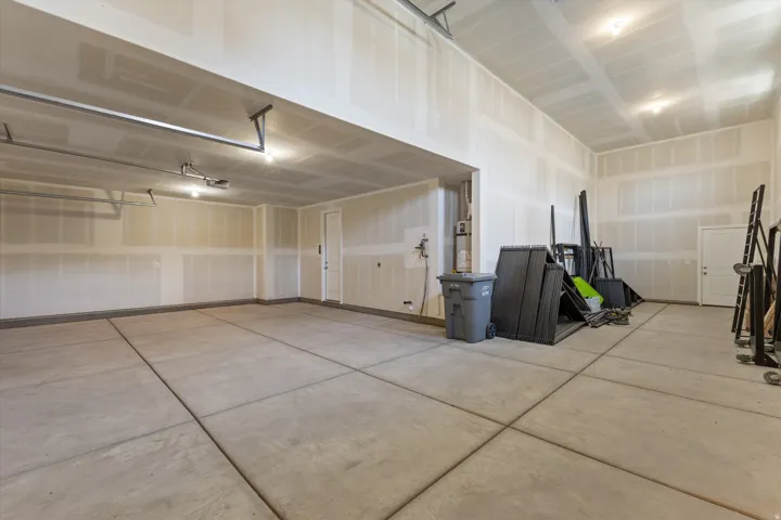 Concrete slab flooring, exposed drywall, overhead lighting, and white doors