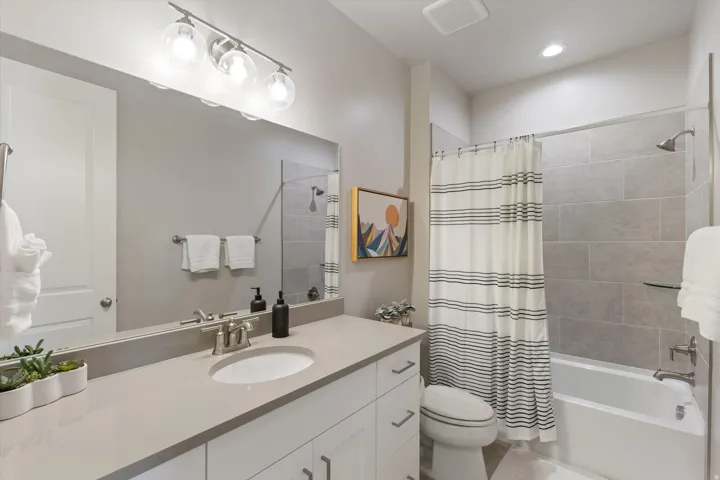Bathroom featuring a single vanity with stone countertop, white cabinetry, undermount sink, and brushed nickel fixtures