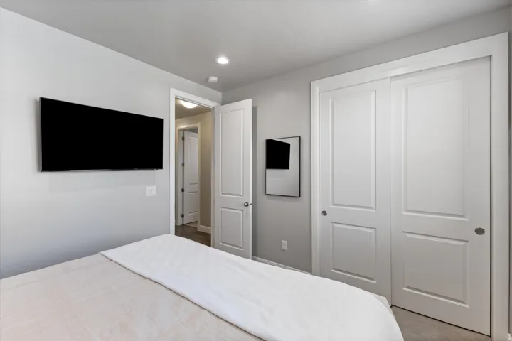 Recessed lighting illuminates the room, featuring a built-in closet with paneled doors and a neutral color palette