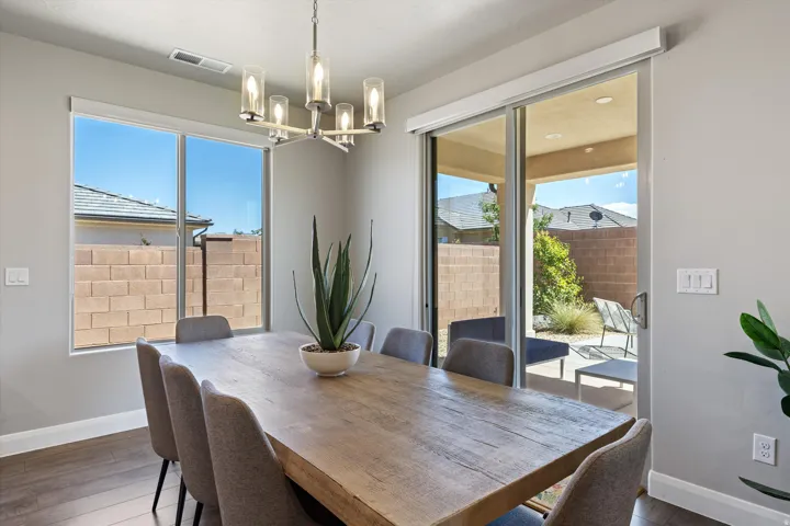 Wood-finish flooring, contemporary chandelier, large windows, and sliding glass door to outdoor area