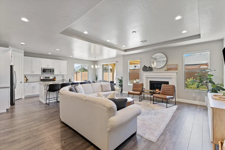 Open-concept living space featuring wood-finish flooring, recessed lighting, and a white kitchen with stainless steel appliances