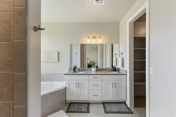 Dual vanity with white cabinetry and chrome hardware, undermount sinks, and a stone countertop
