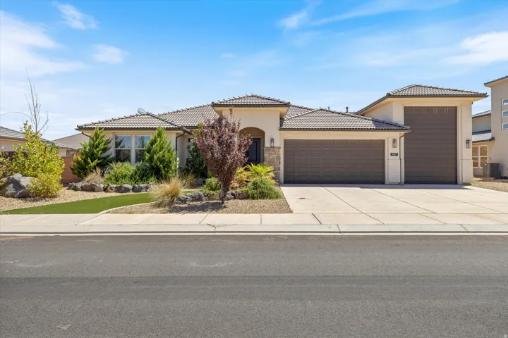 Stucco exterior with stone accents, tile roofing, and a concrete driveway