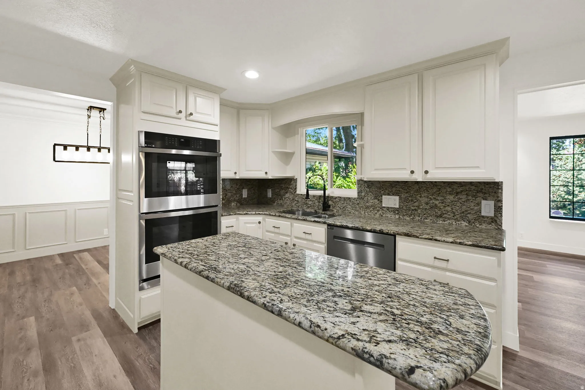 Kitchen featuring white cabinetry, granite countertops, stainless steel double ovens, and a built-in dishwasher