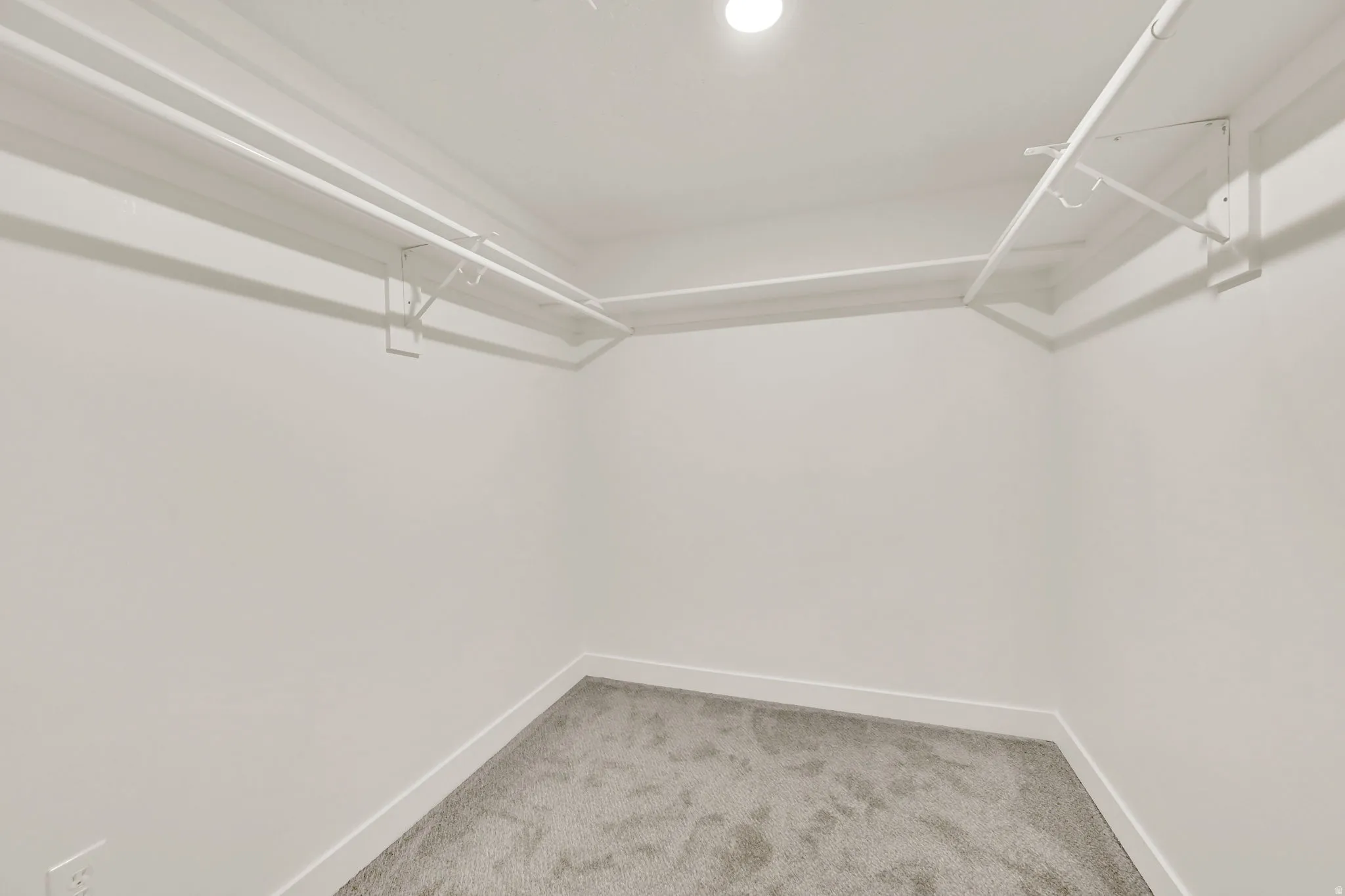 Recessed ceiling lighting, white walls, built-in wire shelving, built-in wire hanging rods, and gray carpet flooring