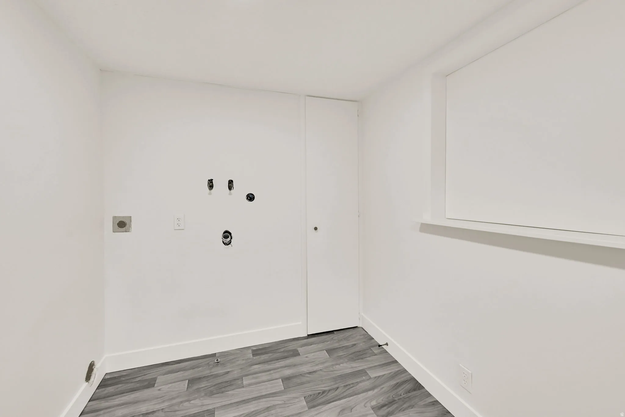 Wood-finish flooring, white walls, and a window with a sill