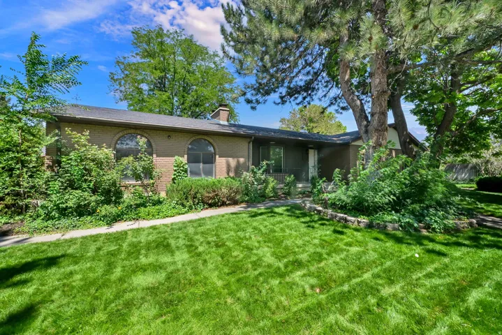Brick exterior with arched windows, mature landscaping, and a manicured front lawn