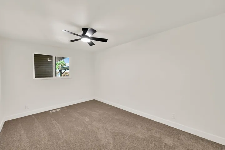 Recessed window with white trim, gray carpeted flooring, and a modern ceiling fan with integrated lighting
