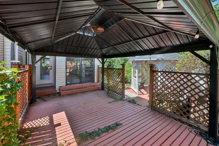 Covered wood-finish deck with privacy lattice, equipped with an overhead light fixture and an outdoor heater