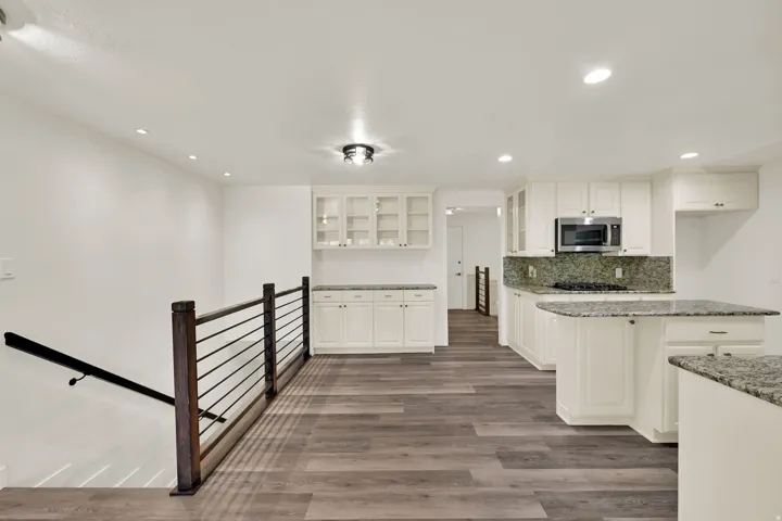Open-concept kitchen with white cabinetry and stone countertops